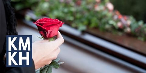 woman with rose in front of coffin